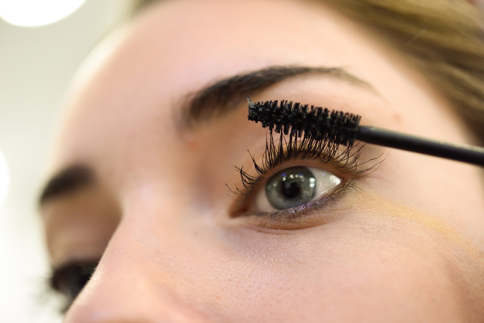Mascara wand and tube next to an eye with lifted, lengthened lashes